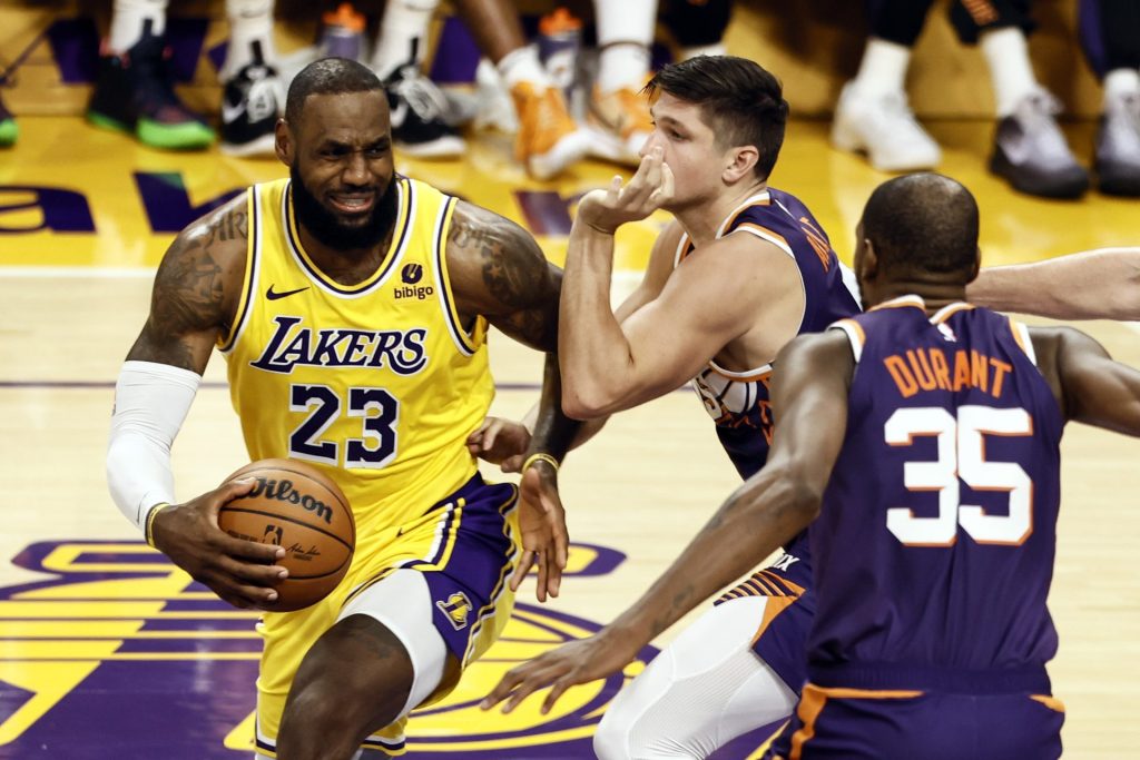 El jugador de Los Angeles Lakers LeBron James (i) enfrenta a sus rivales de los Phoenix Suns Grayson Allen (c) y Kevin Durant (d) durante un partido de la NBA, en una fotografía de archivo. EFE/ Etienne Laurent
