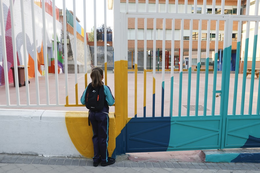 Una niña observa el patio de un colegio.