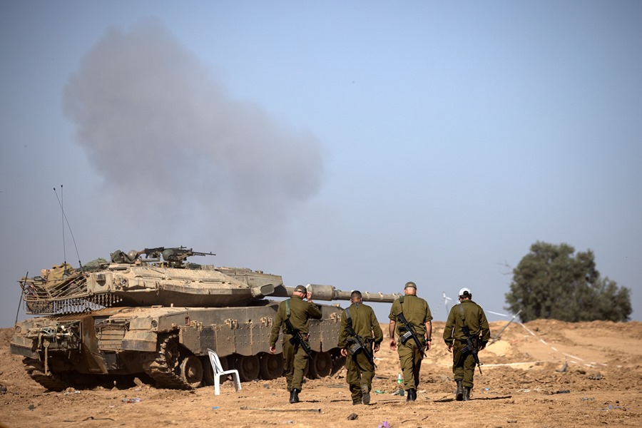 Un grupo de soldados israelíes camina cerca de un tanque en la frontera con la Franja de Gaza