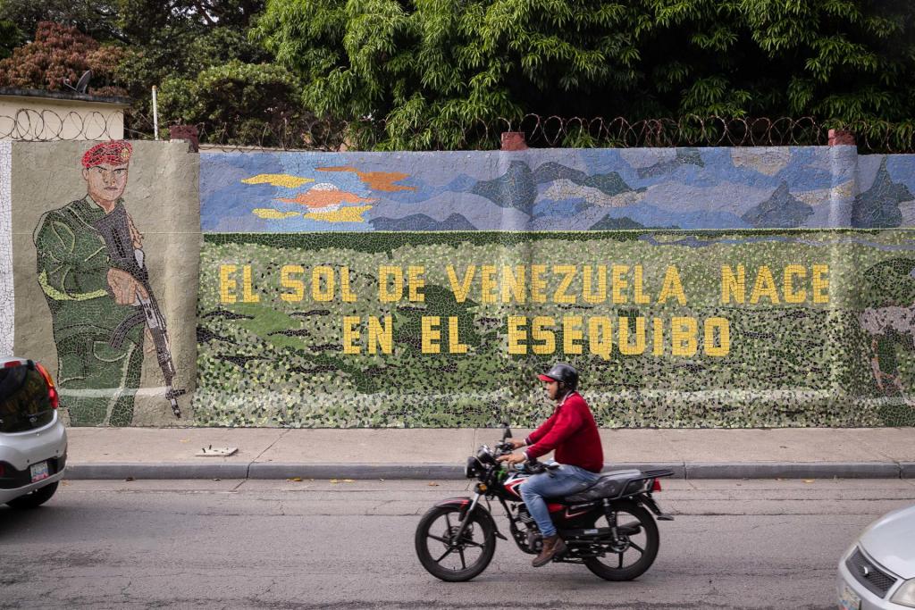 Un hombre conduce una moto frente a un mural que dice "El sol de Venezuela nace por el esequibo", el 2 de noviembre de 2023, en Caracas (Venezuela). EFE/Rayner Peña R.
