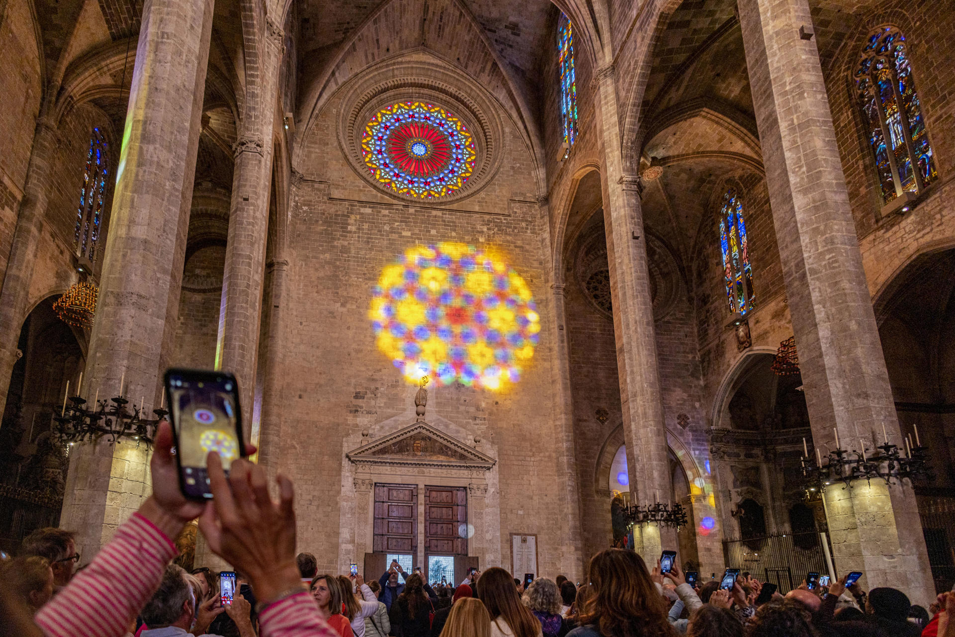 Cientos de personas se han congregado en la Catedral de Mallorca para asistir a la "Fiesta de la Luz", el singular espectáculo que ofrece el sol al entrar por el rosetón, formando un "ocho" que este otoño se ha abierto paso por instantes entre las nubes.- EFE/CATI CLADERA