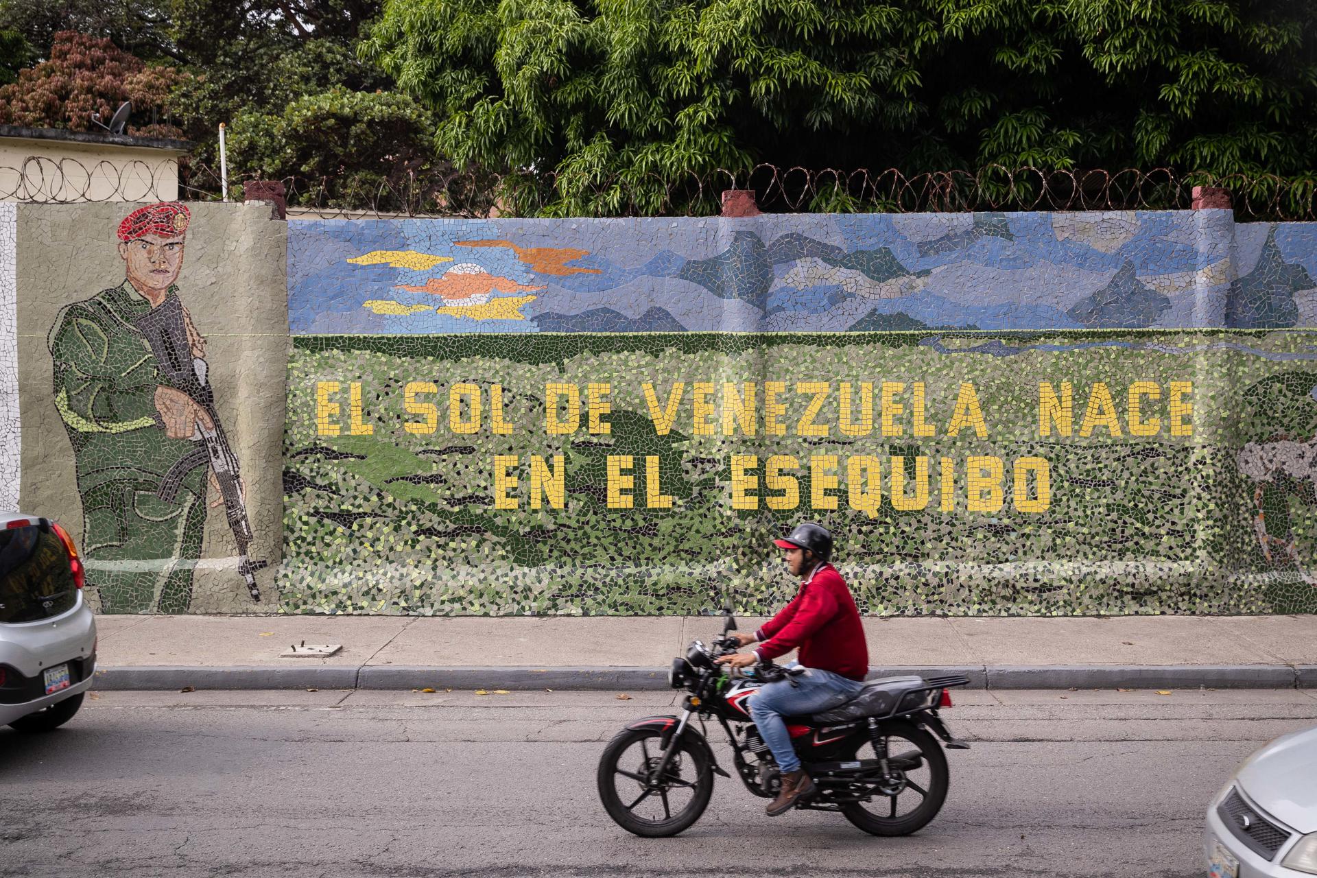 A man rides a motorcycle in front of a mural that reads "The sun of Venezuela is born by the Essequibo", in Caracas, Venezuela, 2 November 2023.   EFE/ Rayner Peña R.