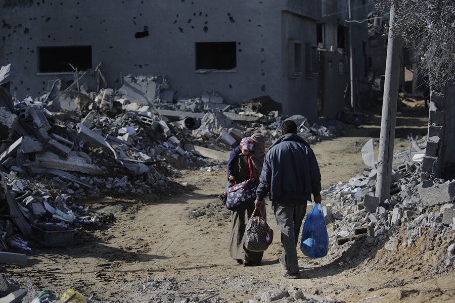 Los palestinos pasan junto a los escombros de las casas destruidas tras los ataques aéreos israelíes nocturnos en el este de Khan Younis