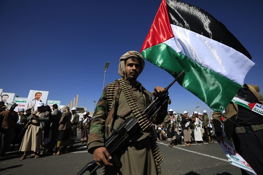 Un recién miembro reclutado del ejército popular de los hutíes sostiene un arma y una bandera palestina durante un desfile en Saná, Yemen