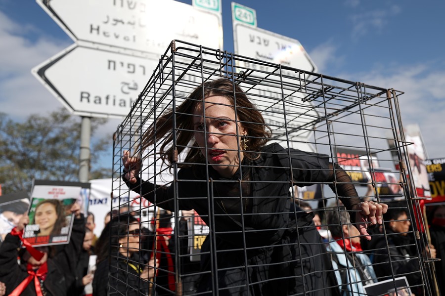 Una activista israelí hace el papel de rehén en el interior de una jaula durante una protesta de familiares de rehenes israelíes en un kibbutz cercano a la frontera de Israel con Gaza