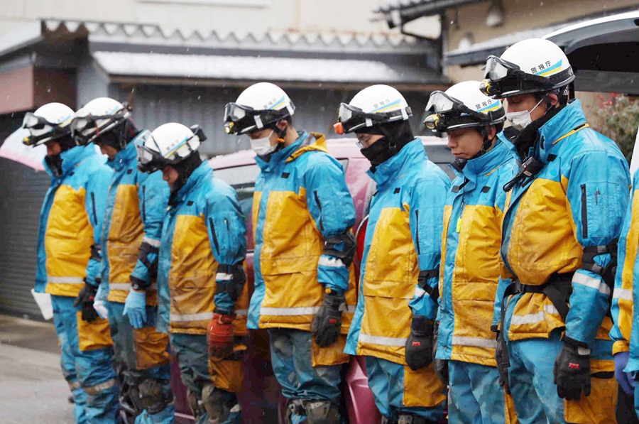 Miembros de las servicios de recate guardan un minuto de silencio tras hallar el cadáver de una víctima del terremoto de Japón