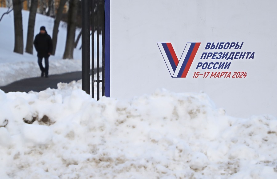 Un hombre camina junto a un cartel de la campaña preelectoral que dice "Las elecciones del presidente de Rusia". 15-17 de marzo de 2024' en Moscú