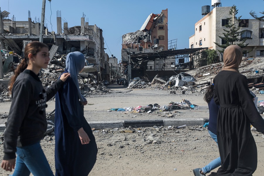 Varias mujeres palestinas pasan junto a edificios destruidos en el campo de refugiados de Al Nuseirat, en el centro de la Franja de Gaza, tras los ataques aéreos israelíes