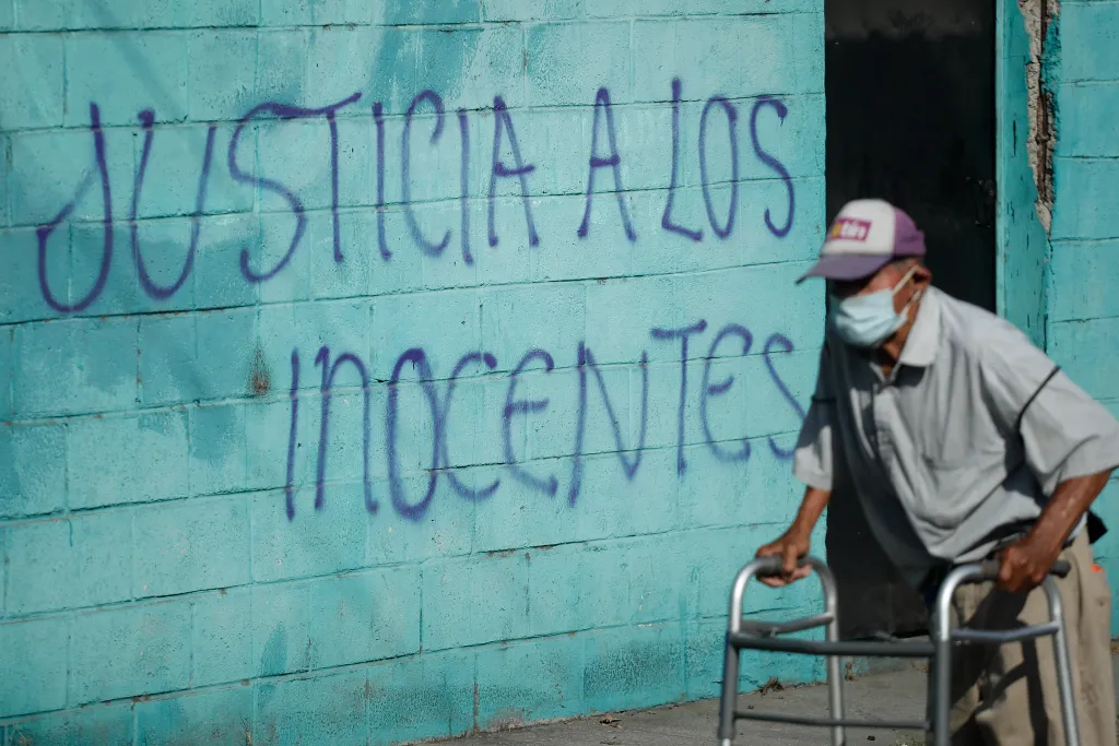 Imagen de archivo de un hombre frente a una pared pintada con la frase 'Justicia a los inocentes' en Soyapango (El Salvador), donde el Gobierno de Bukele ha prometido acabar con las maras a pesar de las denuncias por violaciones de DD.HH.